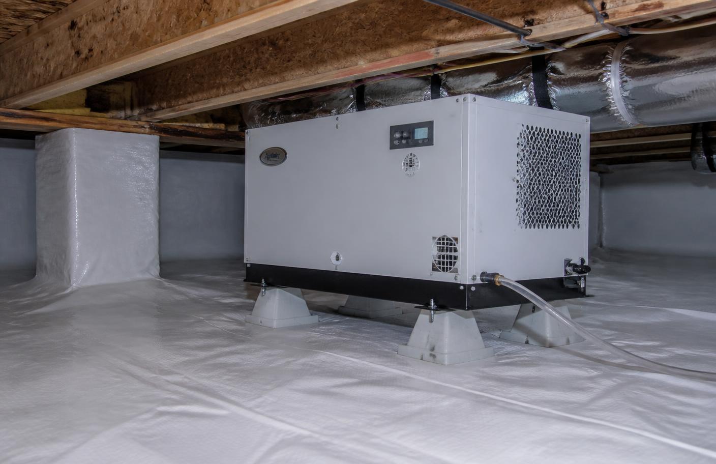 Crawl space dehumidifier installed on blocks over a sealed white liner